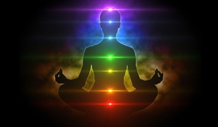 A meditating silhouette with the seven chakras lit in their colours, root to crown